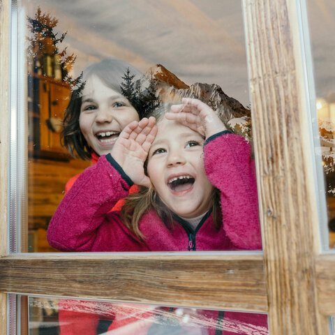 Zwei Mädels schauen aus einem Fenster