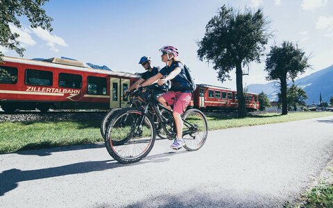 Zwei Fahrradfahrer radeln entlang eines Bahngleises.