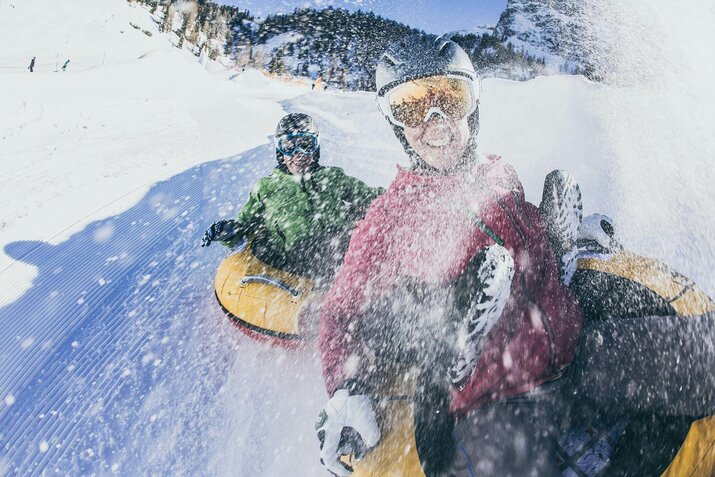 Zwei Personen fahren auf  luftgefüllten Reifen die Piste hinunter