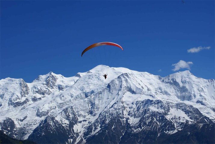 Ein Paragleiter zieht über die Gipfel der Berge