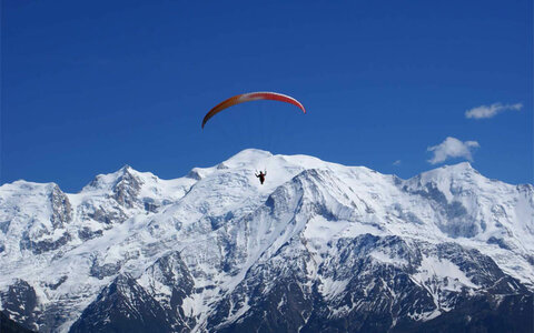 Ein Paragleiter zieht über die Gipfel der Berge