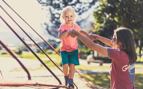 Eine Frau und ein kleines Mädchen spielen auf dem Spielplatz