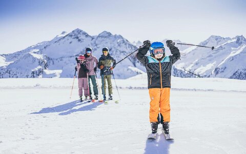 Eine Frau, ein Mann und zwei Kinder stehen auf der Piste auf ihren Skiern