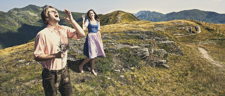 Ein Mann und eine Frau in Trachtenkleidung vor einer traumhaften Berglandschaft