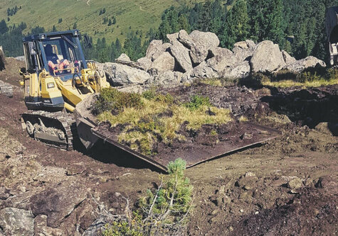 Ein gelber Bagger arbeitet am Pistenbau