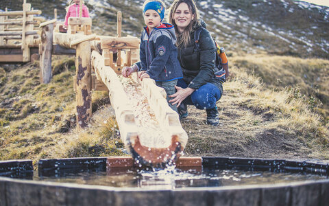 Eine Frau und ein kleiner Junge spielen am Wasserspielplatz