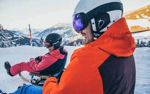 Zwei Rodler fahren die Strecke hinunter