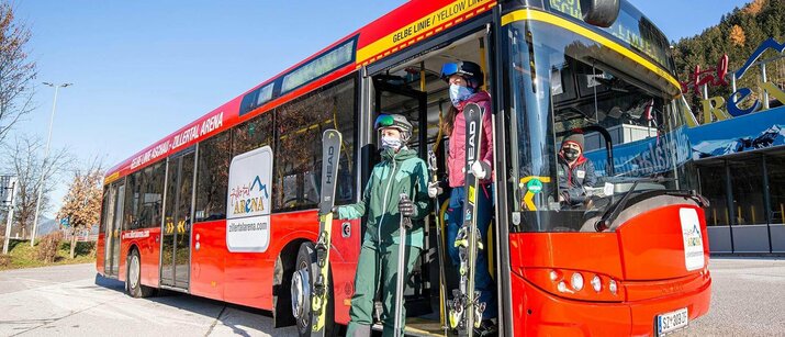 Skifahrer steigen aus einem roten Bus aus