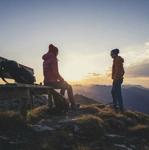 Ein Mann und eine Frau beobachten einen Sonnenaufgang am Kreuzjoch