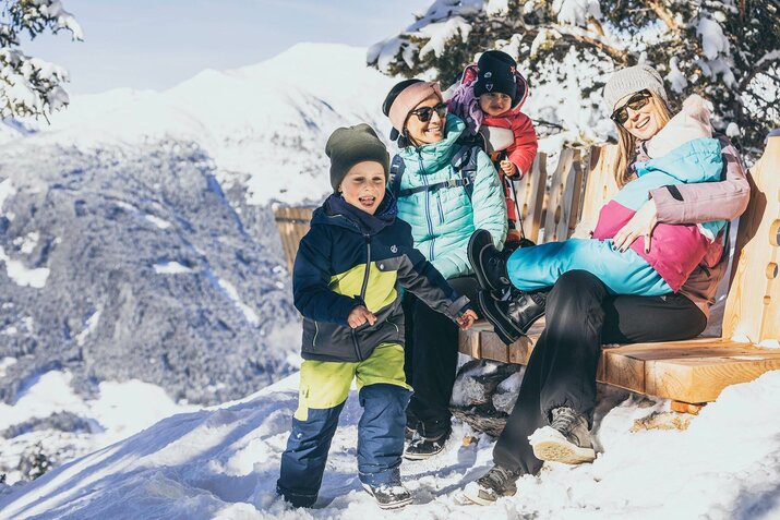 Zwei Frauen und drei Kinder sitzen vor einer traumhaften Bergkulisse