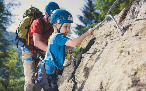 Ein Mann und ein kleiner Junge klettern im Klettersteig Talbach