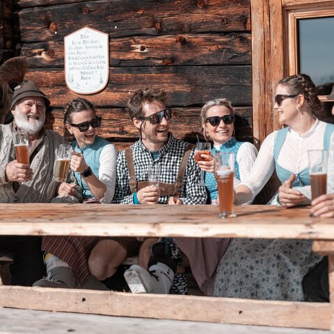 Drei Männer und drei Frauen trinken Bier auf einer Hütte