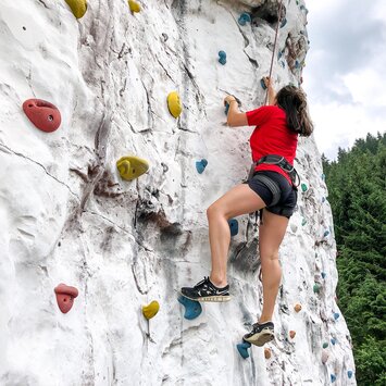 Eine Frau klettert an einer Kletterwand