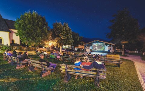 Zuschauer sitzen auf Holzbänken beim Fallkino Krimml
