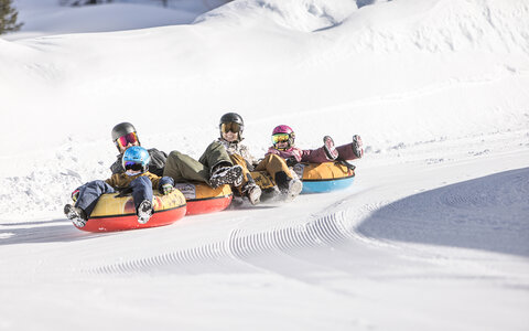 Eine Familie fährt auf luftgefüllten Reifen die Piste hinunter