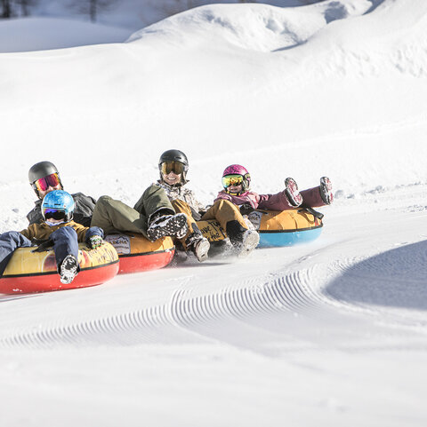 Eine Familie fährt auf luftgefüllten Reifen die Piste hinunter