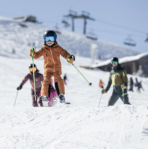 Ein kleiner Junge rast auf Skiern über die Piste