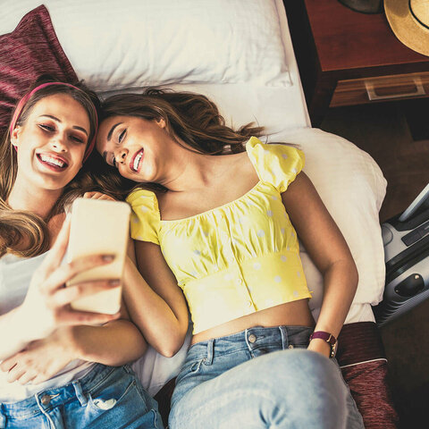 Zwei Frauen liegen auf einem Bett und machen ein Selfie