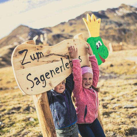 Zwei Kinder stehen an einem Holzschild