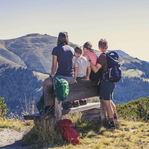 Eine Familie sitzt auf einer Bank und beobachtet eine traumhafte Bergkulisse