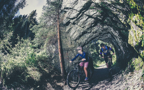 Zwei Radfahrer fahren durch eine kurze Steintunnel.