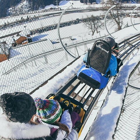 Eine Familie fährt auf der Winterrodelbahn