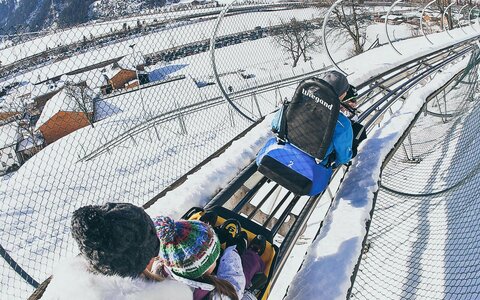 Eine Familie fährt auf der Winterrodelbahn