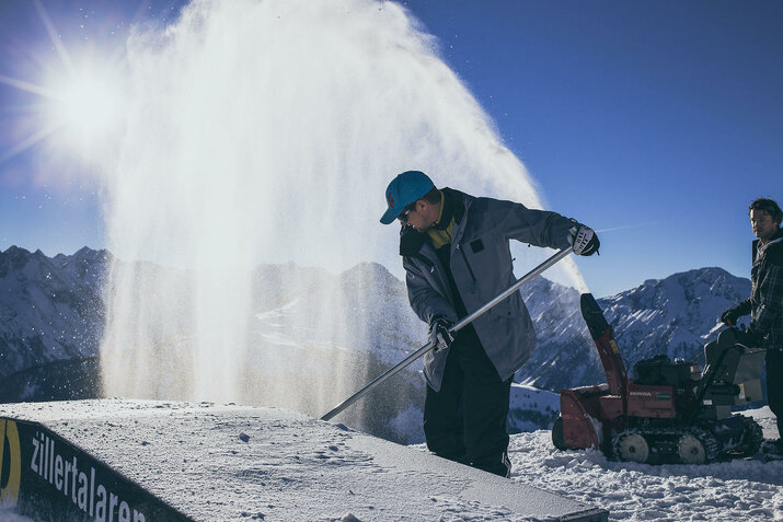 Zwei Männer arbeiten auf einer verschneiten Piste.