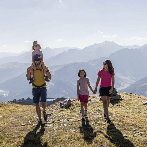 Ein Mann, eine Frau und zwei Mädchen wandern durch eine schöne Berglandschaft