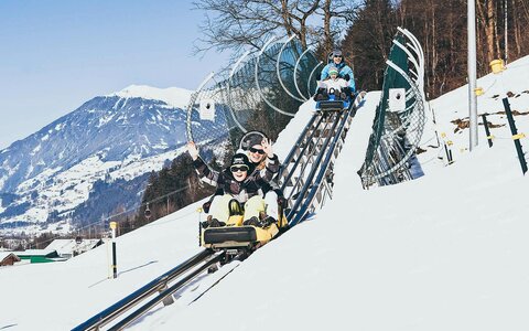 Eine Familie fährt mit der Winterrodelbahn