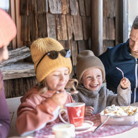 Eine Familie genießt Kakao und Kaiserscharren auf einer Hütte