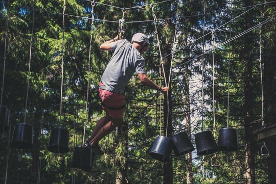 Ein Mann klettert im Hochseilgarten