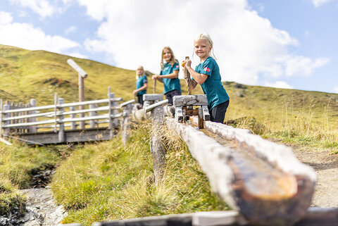 Drei Kinder spielen am Wasserspielplatz