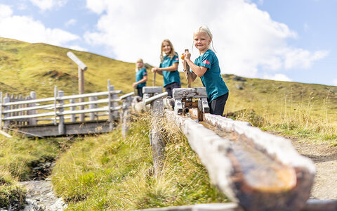 Drei Kinder spielen am Wasserspielplatz