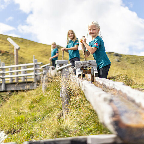Drei Kinder spielen am Wasserspielplatz