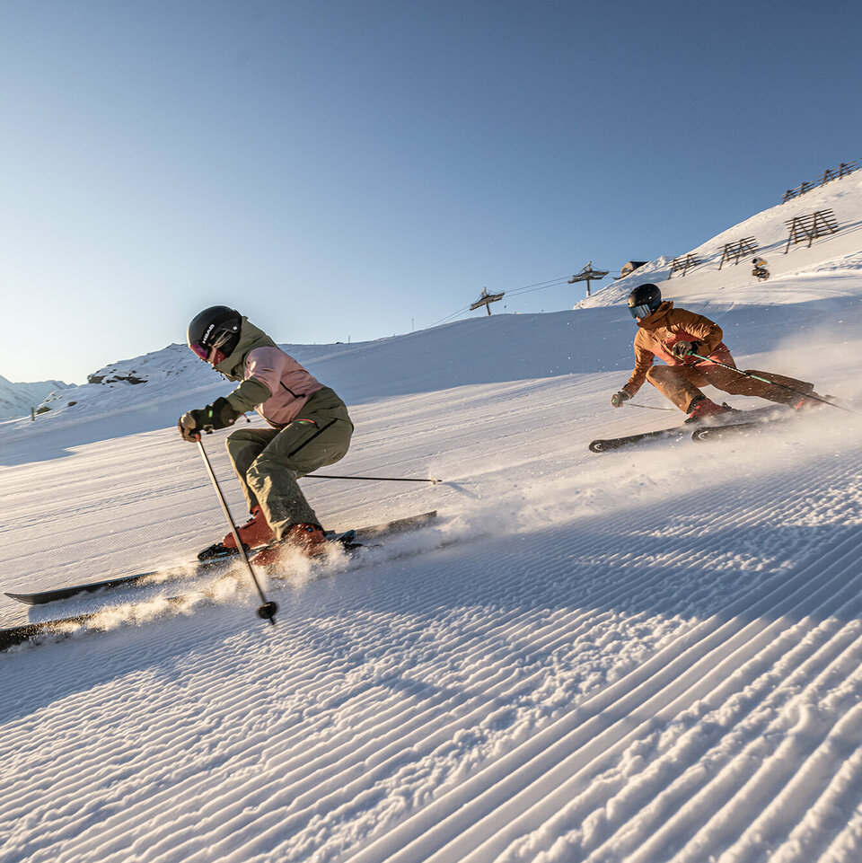 Zwei Skifahrer fahren eine Piste hinunter