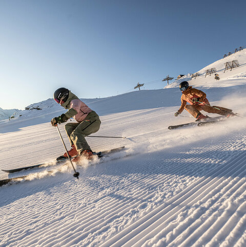 Zwei Skifahrer fahren eine Piste hinunter