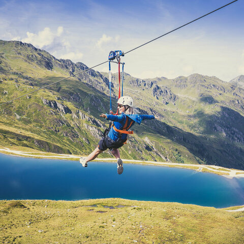 Eine Frau fährt mit einer Zipline über der traumhaften Natur