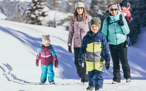 Zwei Frauen und drei Kinder spazieren im Schnee