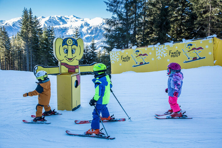 Drei Kinder fahren die Funty Piste hinunter