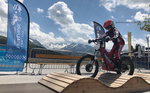 Ein Junge fährt mit einem E-Trial-Bike über einen Parcours