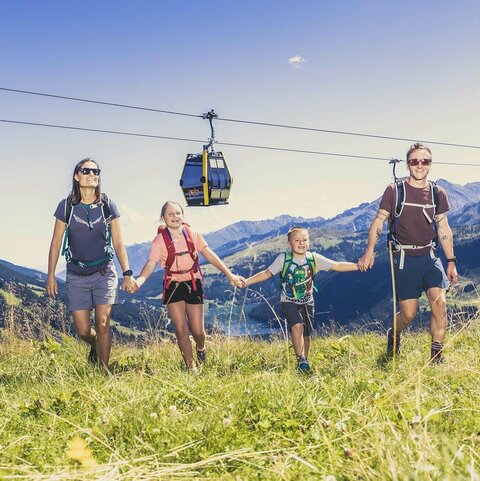Eine Familie spaziert händchenhaltend durch eine Wiese