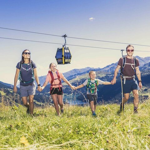 Eine Familie spaziert händchenhaltend durch eine Wiese