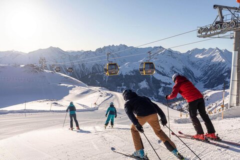 Vier Skifahrer fahren die Piste hinunter