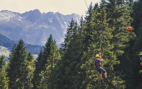 Eine Mann fährt mit einer Seilrutsche durch den Wald