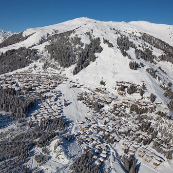 Blick auf ein schneebedecktes Dorf mit verschneiten Häusern und winterlichen Landschaften